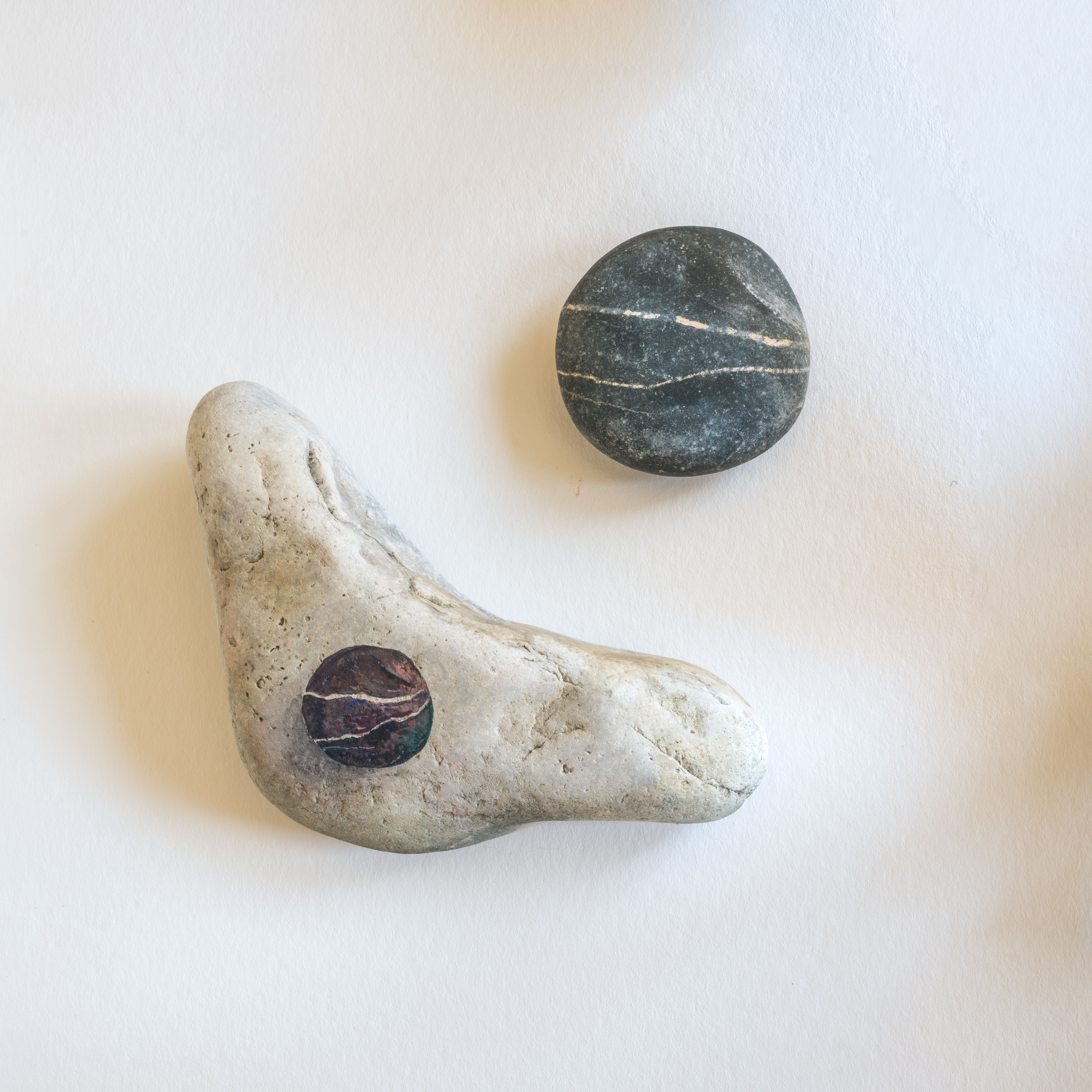 Tales of Pebbles - A miniature installation: two pebbles with one watercolour-painted portrait of a pebble on another pebble rock's flat surface